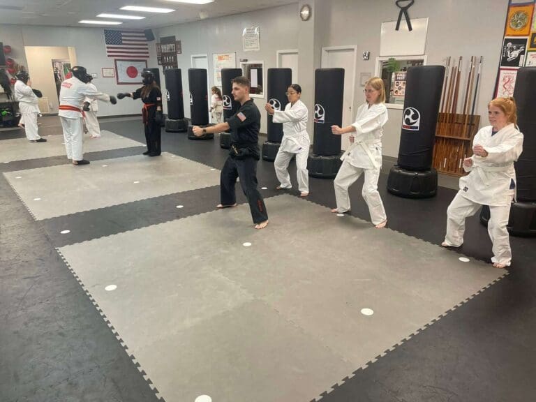 Karate students practicing basic techniques during an adult karate class while demonstrating the front stance in karate.